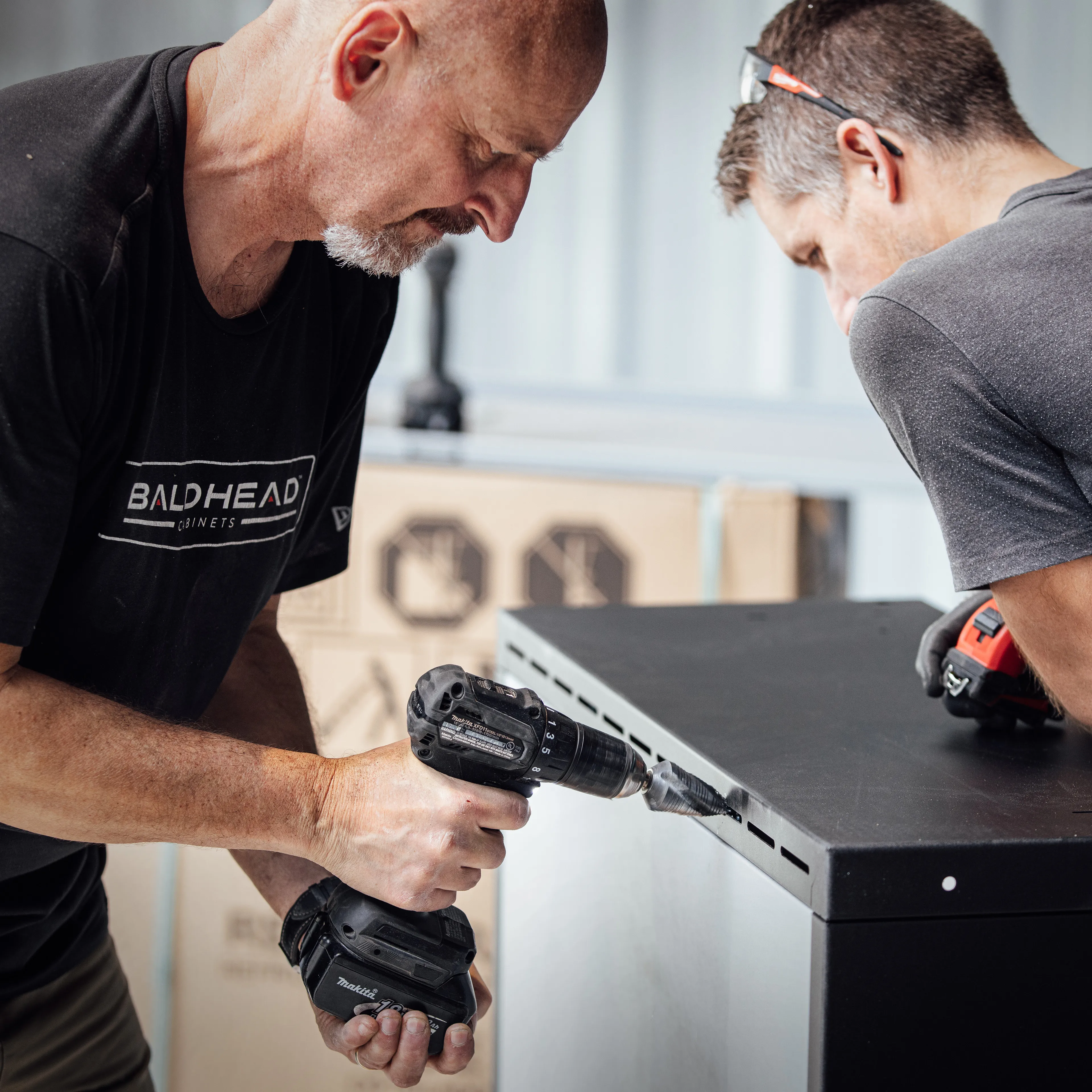 Two individuals assembling cabinetry, working on a black cabinet, showcasing professional cabinet installation project