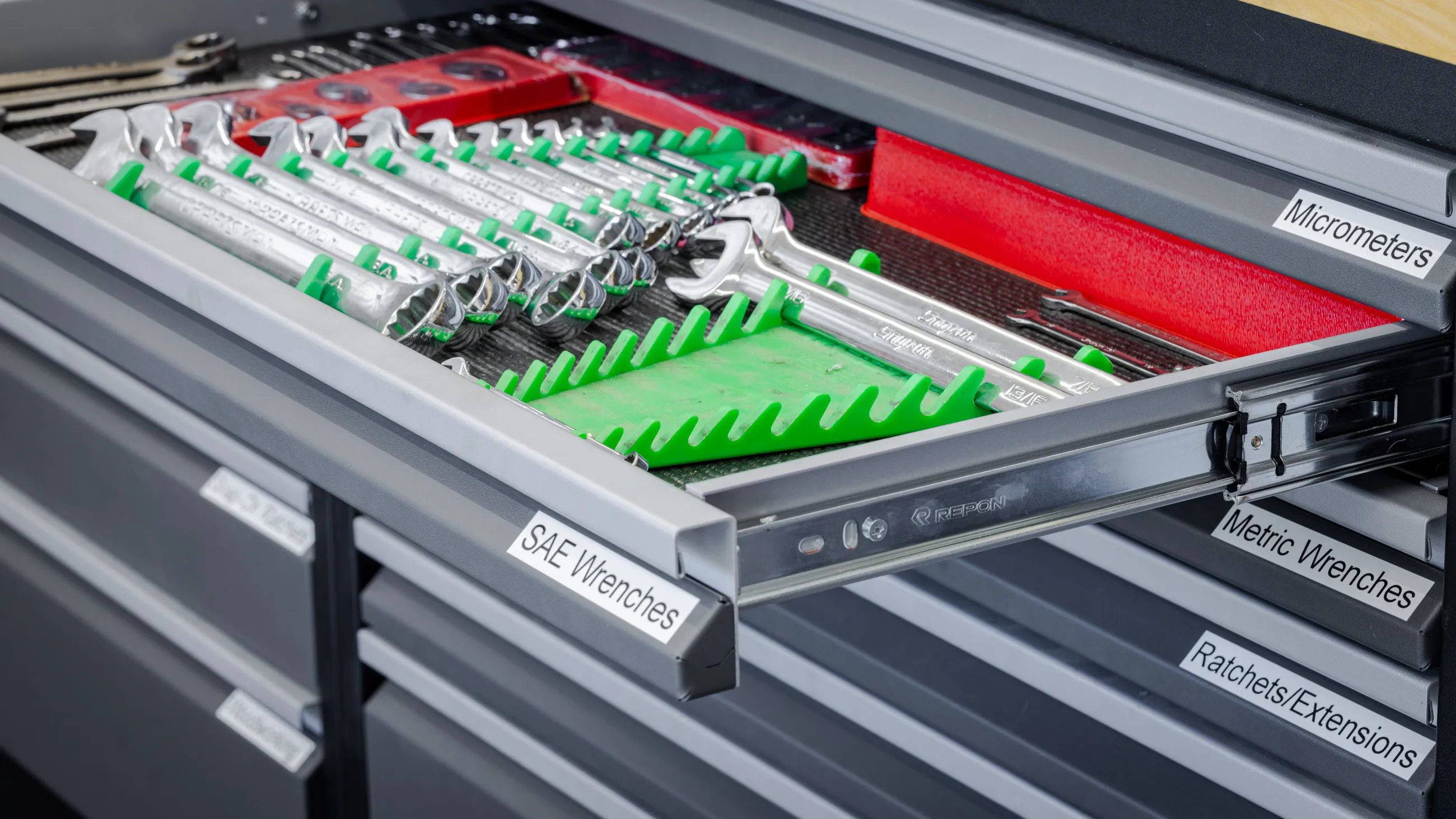 Close-up of a Baldhead Cabinets drawer featuring organized SAE and metric wrenches, micrometers, and ratchets/extensions, stored in labeled heavy-duty drawers with smooth Repon slides, showcasing professional-grade garage tool storage.