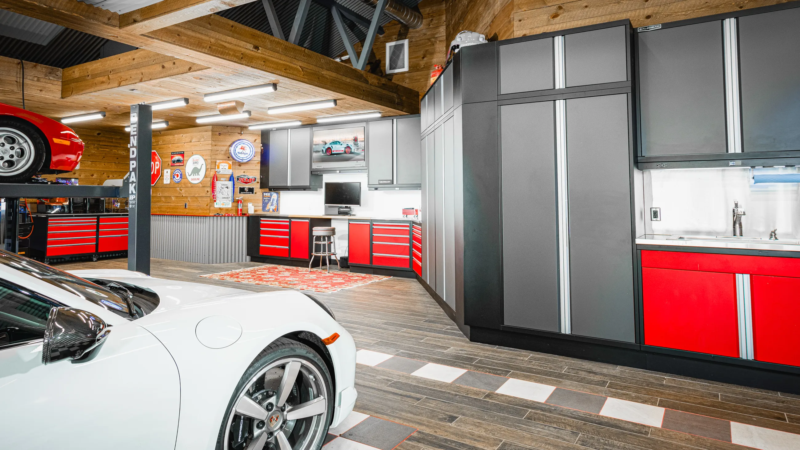 Luxury custom garage featuring Baldhead Cabinets’ premium red and gray modular storage solutions, high-end finishes, and organized workspaces with integrated tool storage and workbenches—perfect for automotive enthusiasts and professionals.