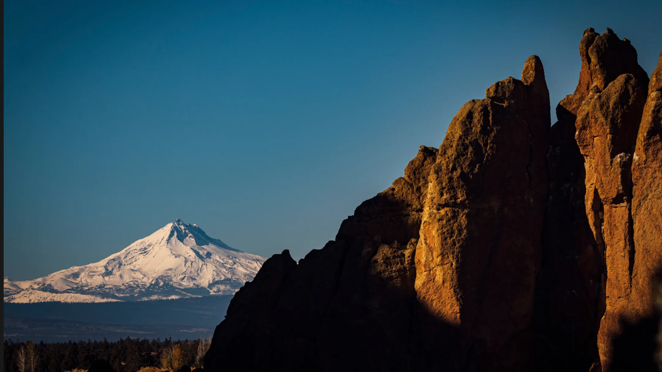 A majestic snowy peak rises above rugged rock formations, hinting at the inspiring environment of Bald Head Cabinets.